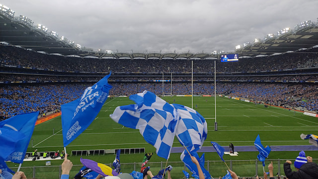 Packed Croke Park during Leinster vs Northampton in the Investec Champions Cup, with blue supporter flags and competition branding visible.