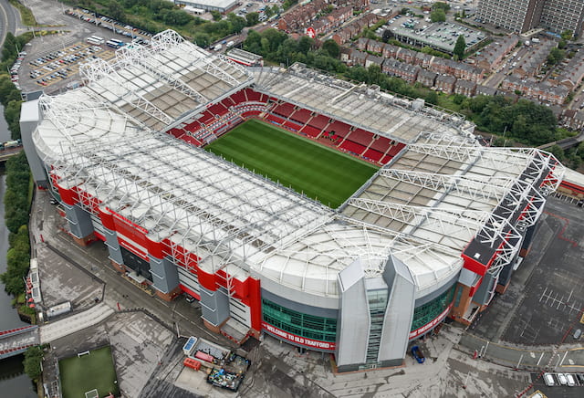 Aerial view of Manchester United’s Old Trafford stadium, showing the pitch, red seating and surrounding streets.