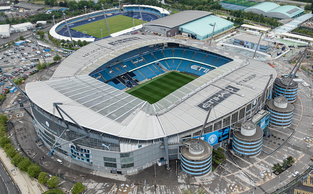 Aerial view of Manchester City’s Etihad Stadium, showing the pitch, blue seating and stadium exterior.