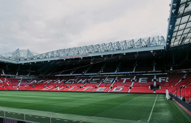 Old Trafford's green pitch and red seating in the Sir Alex Ferguson Stand