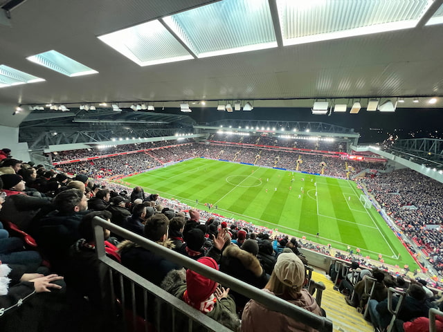 Fans watching a football match at Anfield stadium under floodlights